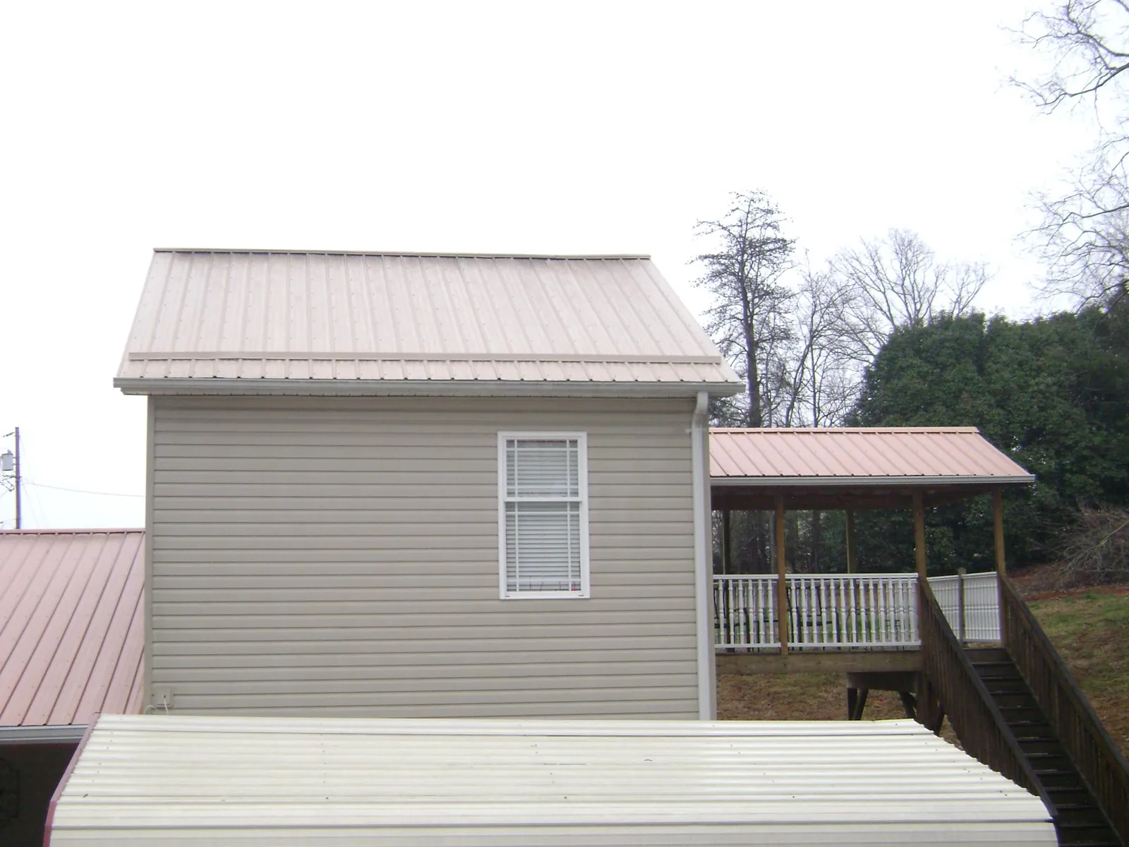 Tan metal roofs on a two story addition and attached porch, from a Roof Replacement job in Thomasville